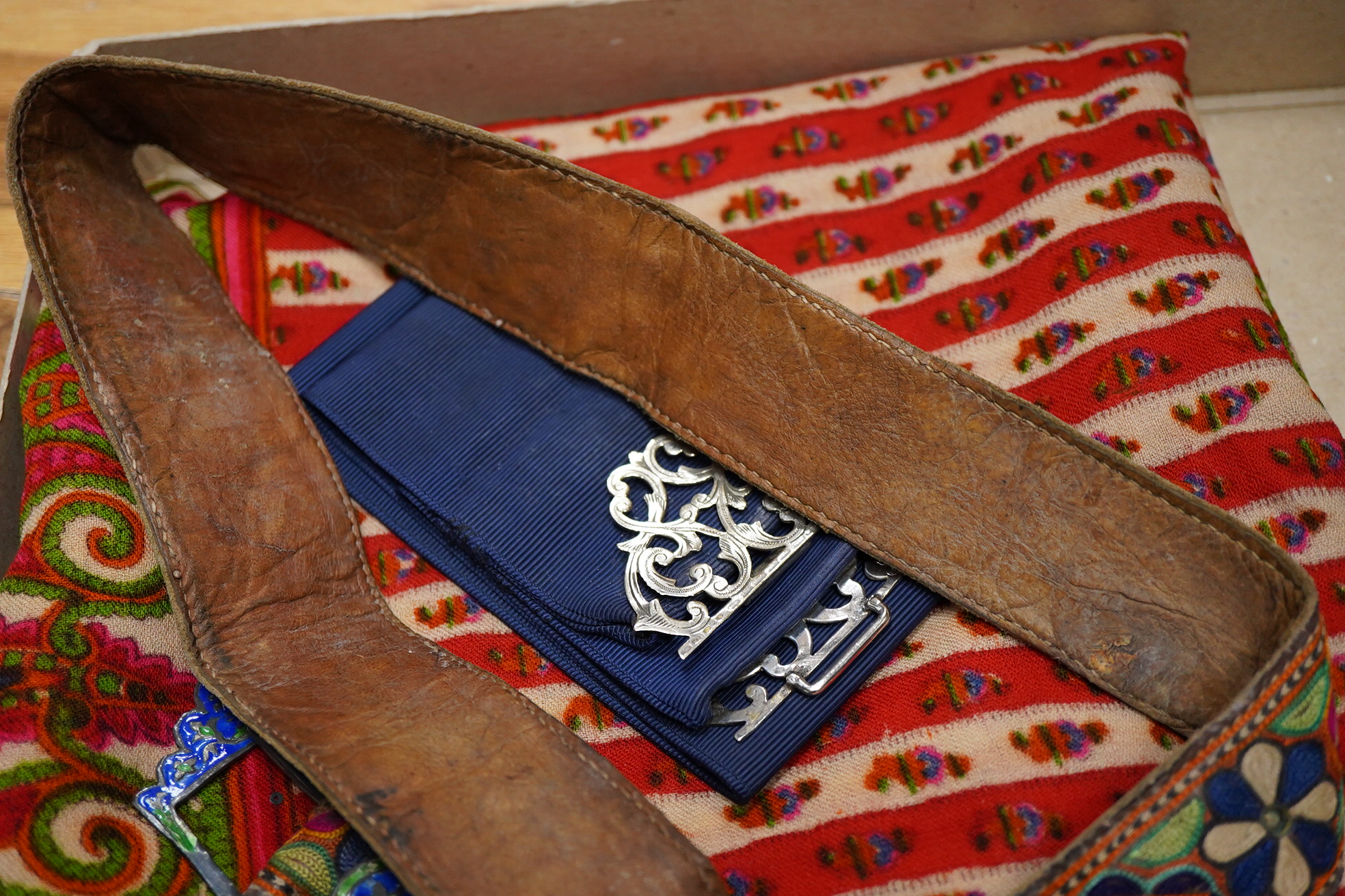 A collection of textiles: a ribbon work hankie and pyjama case, a metalwork collar, a coloured printed shawl, a nurses belt and embroidered belt, an advertising Guggenheim Bilbau hankie etc (10). Hankie case 22cm square.